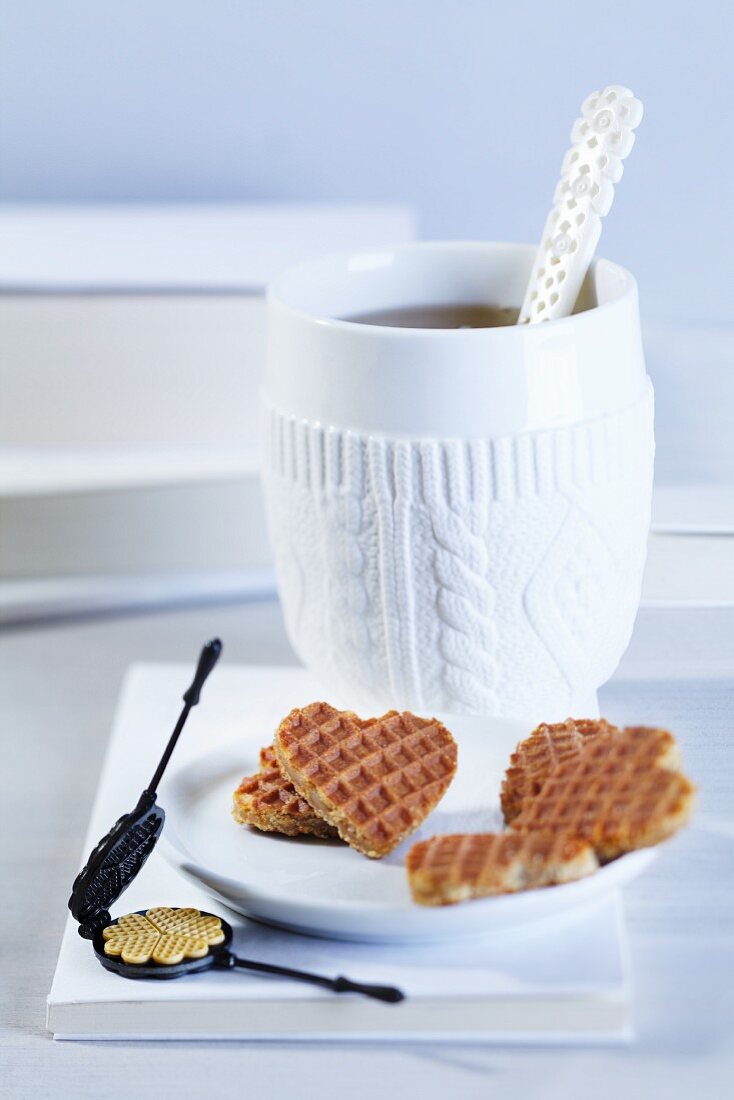 A cup of tea, heart-shaped waffles and a mini waffle iron