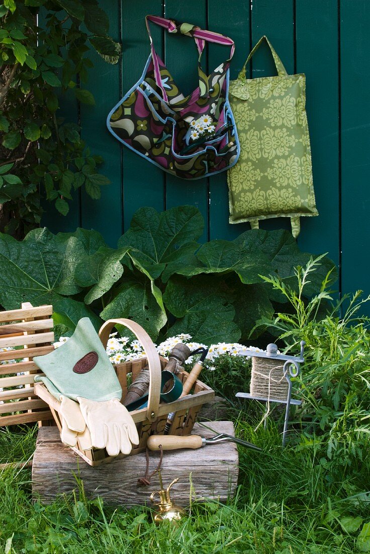 Korb mit Gartenutensilien auf einem Holzblock im Garten