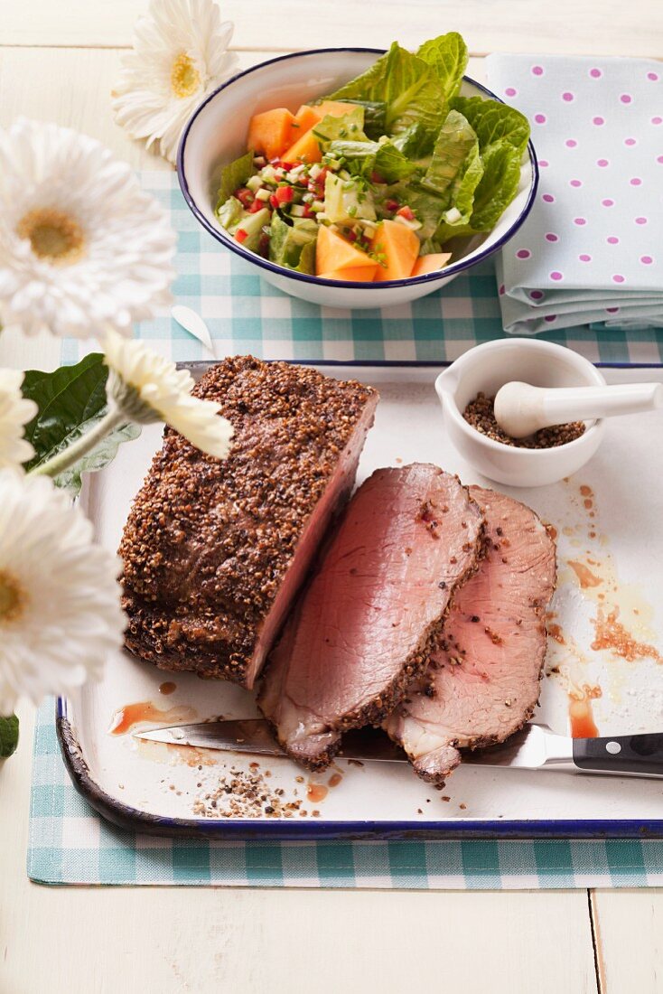 Roast beef with a pepper crust and a melon salad