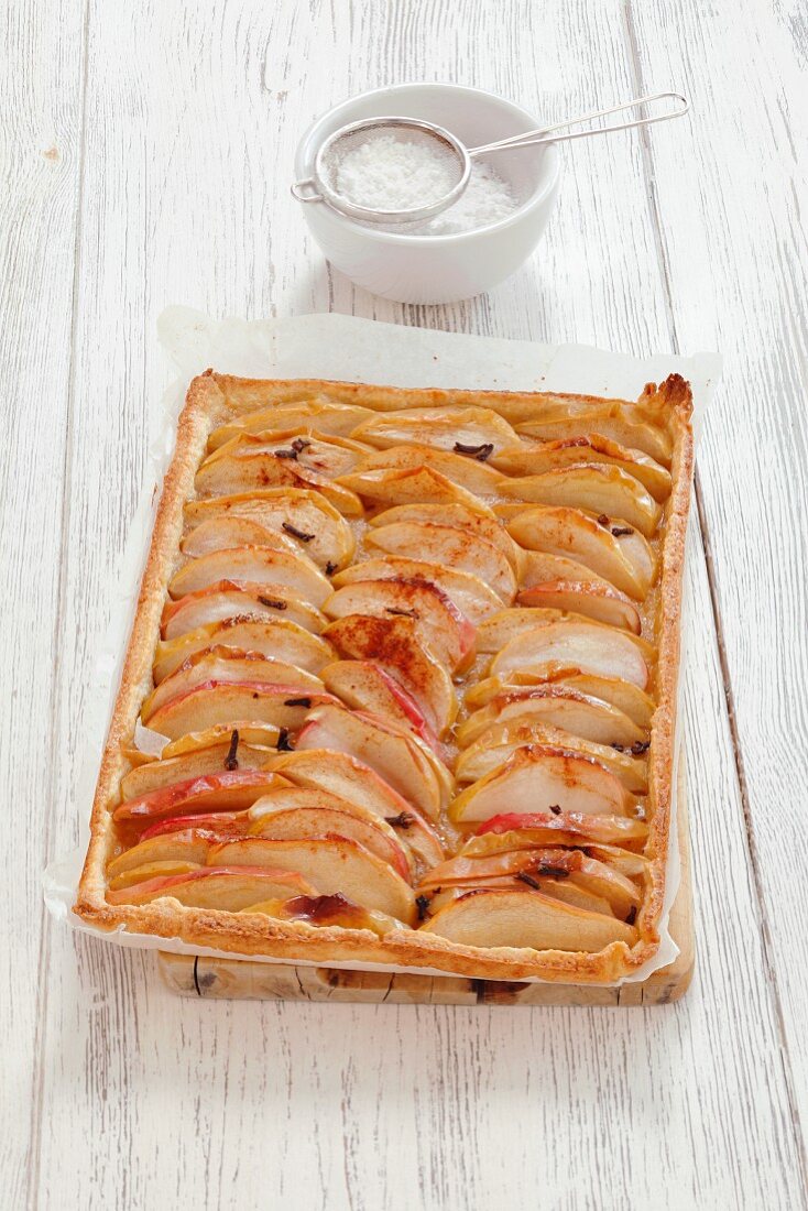 A whole apple and cinnamon tart with icing sugar
