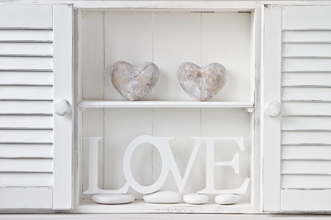 Cabinet holding white-painted wooden letters and stone heart sculptures