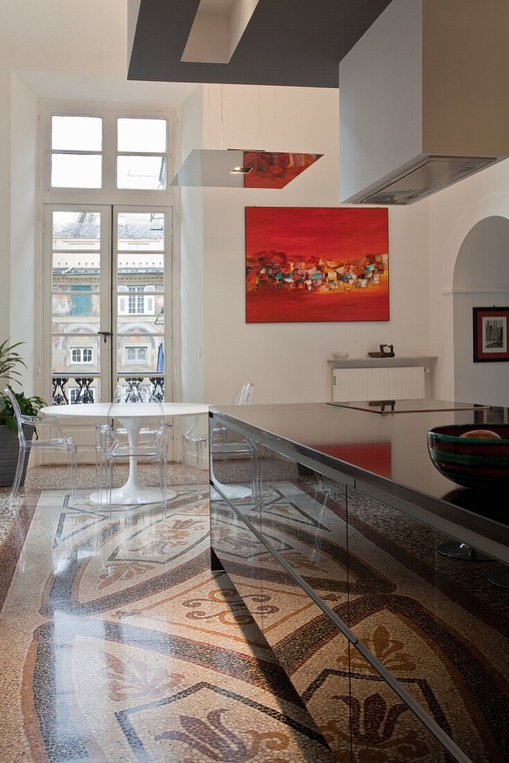 Designer furnishings and Bauhaus style in open-plan kitchen with traditional ambiance - black kitchen island on terrazzo floor with ornamental pattern in front of Bauhaus dining table