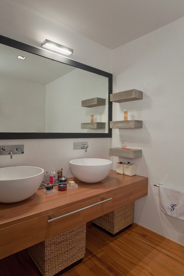 Minimalistisches Designerbad mit weissen Keramikschüsseln auf Waschtisch aus Holz und Wandspiegel