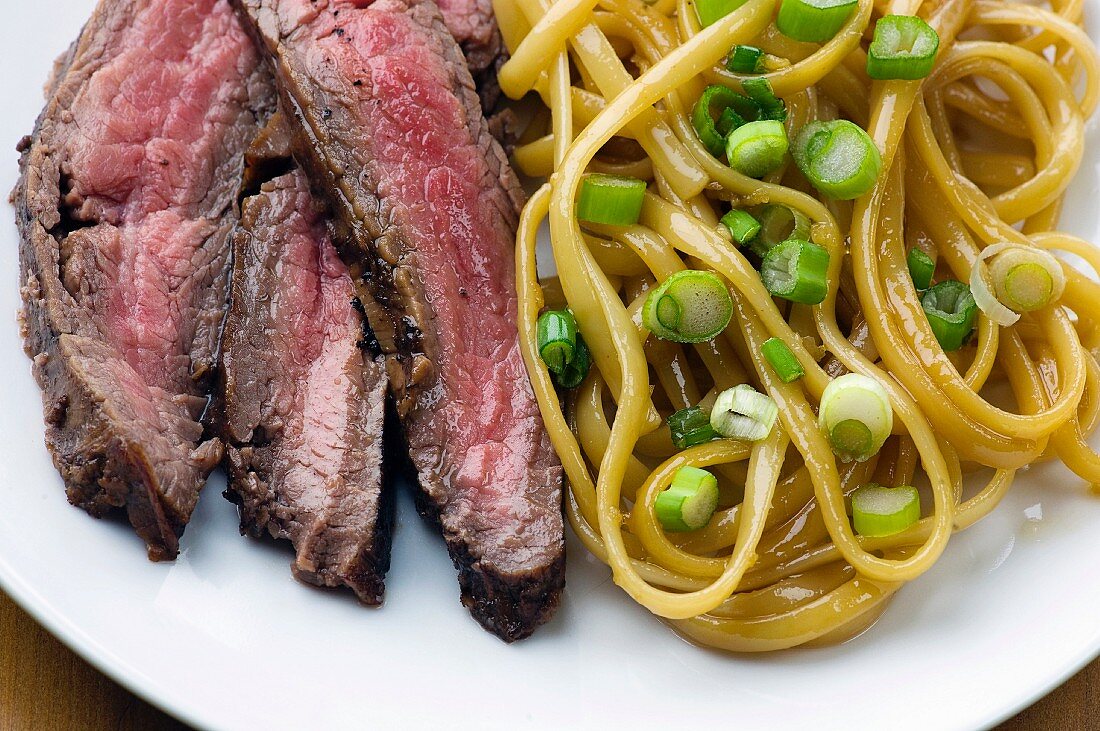 Sliced Steak with Sesame Noodles with Scallions; On a Plate From Above