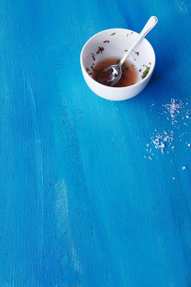 A bowl of dressing on a blue surface