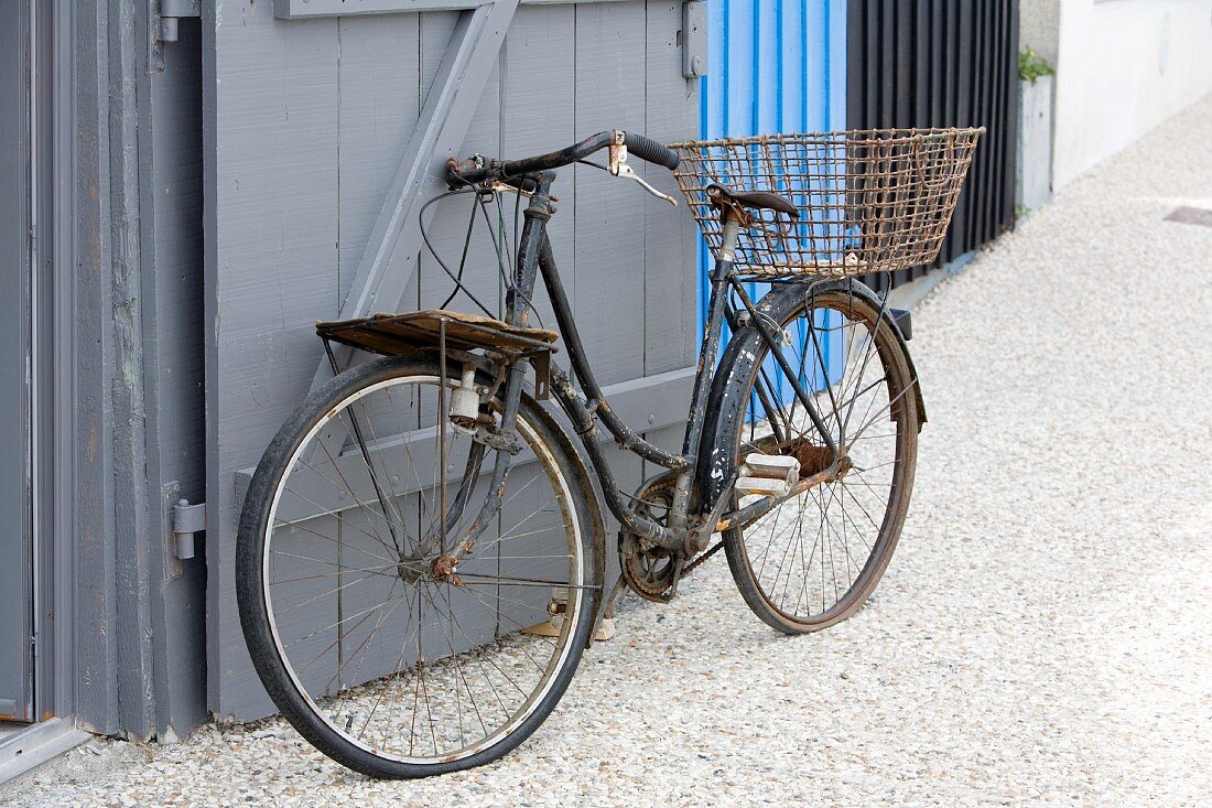 Rusty vintage bicycle leaning on wooden gate