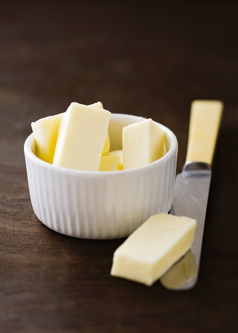 Pieces of butter in a small bowl and on a knife