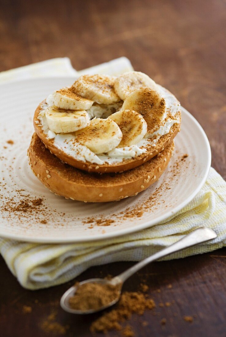 A bagel topped with cream cheese, banana and cinnamon