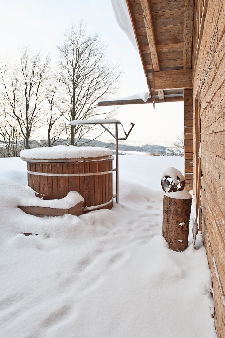 Well next to wooden house in winter landscape