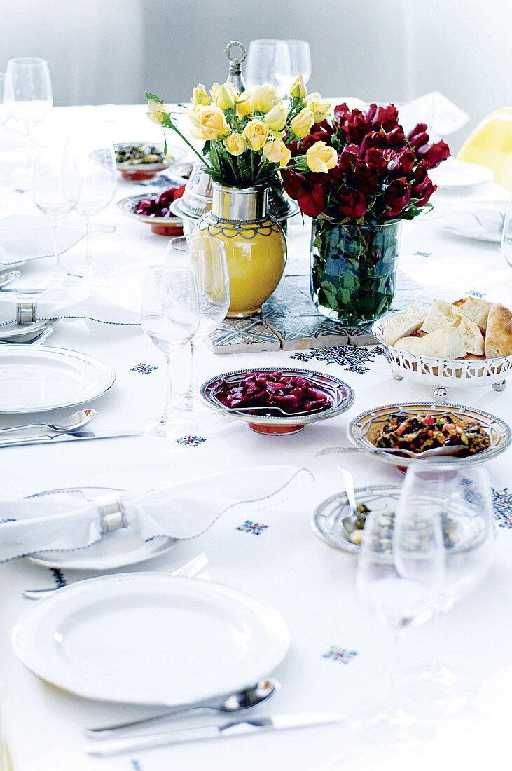 A festively laid table with bunches of flowers, anti-pasti platters and a silver bread bowl