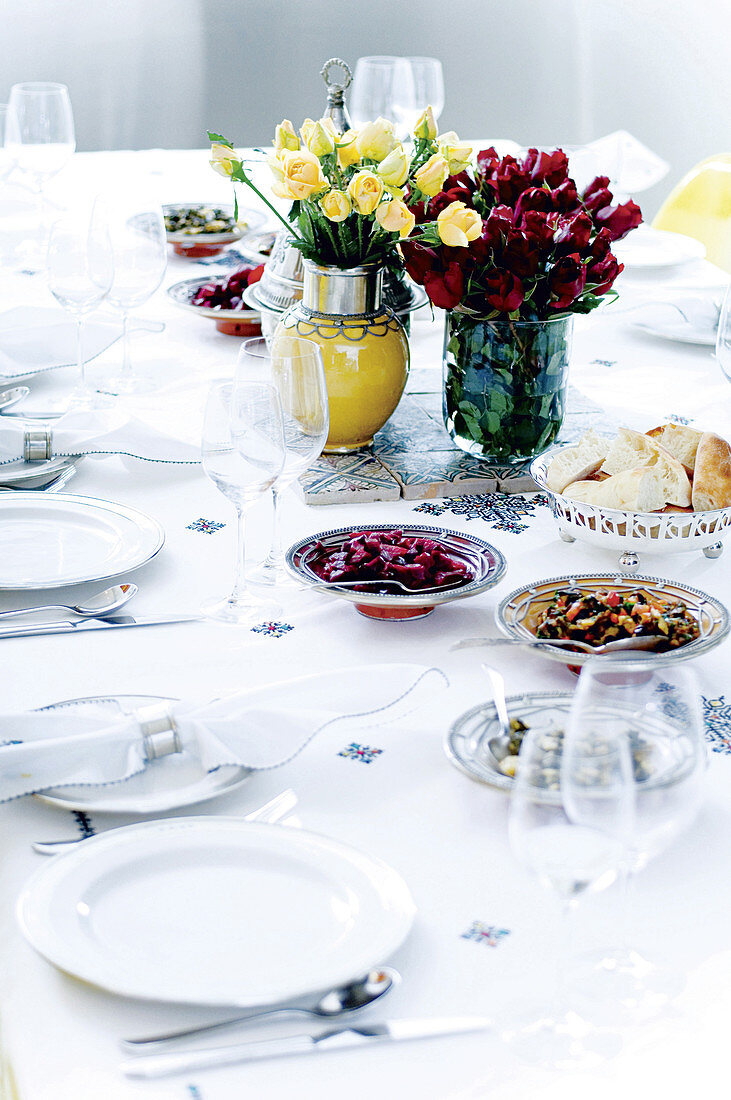 Festlich gedeckte Tafel mit Blumensträussen, Vorspeisentellern und silbernen Brotschalen