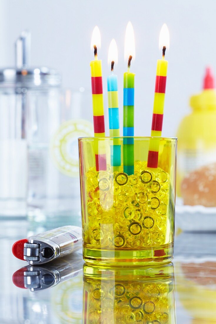 Party candles and decorative pebbles in glass