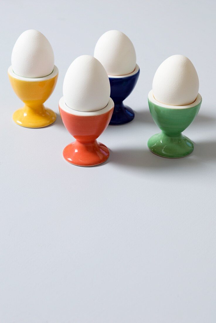 Four White Hard Boiled Eggs in Colorful Egg Cups