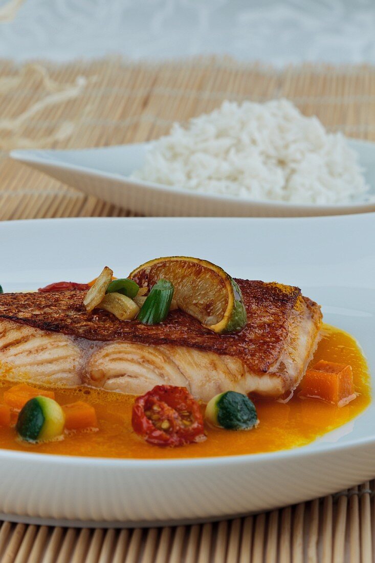 Fish with a vegetable sauce, limes and a side of rice