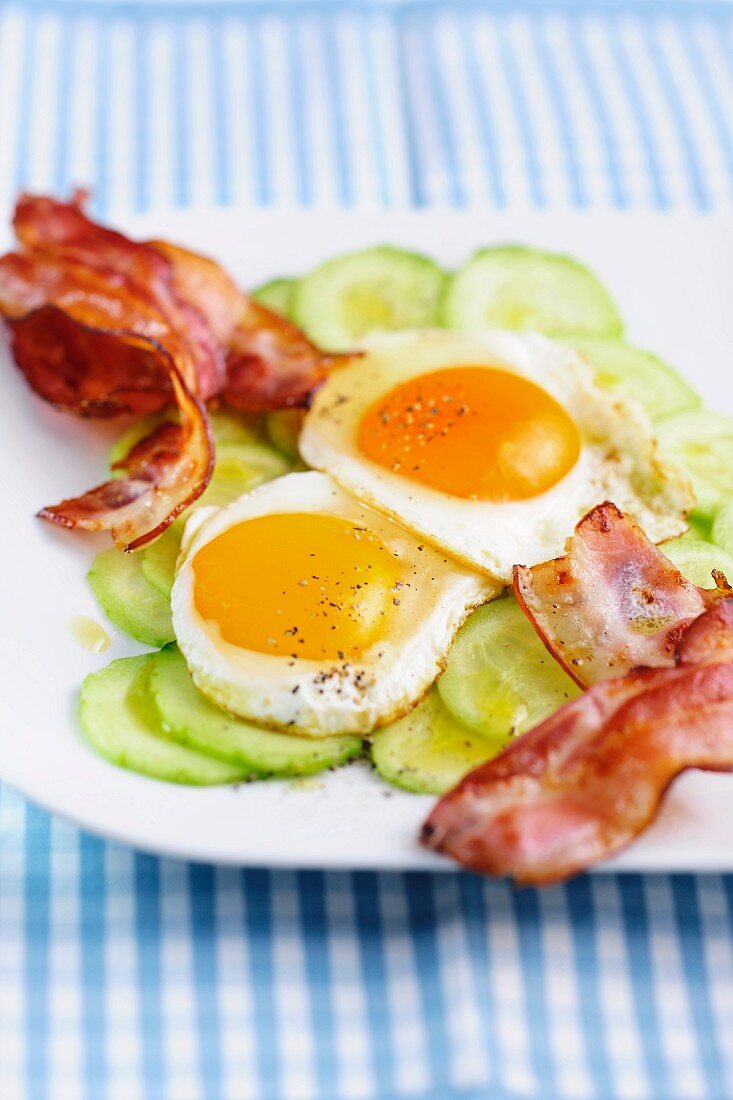 Fried egg with bacon on a bed of cucumber