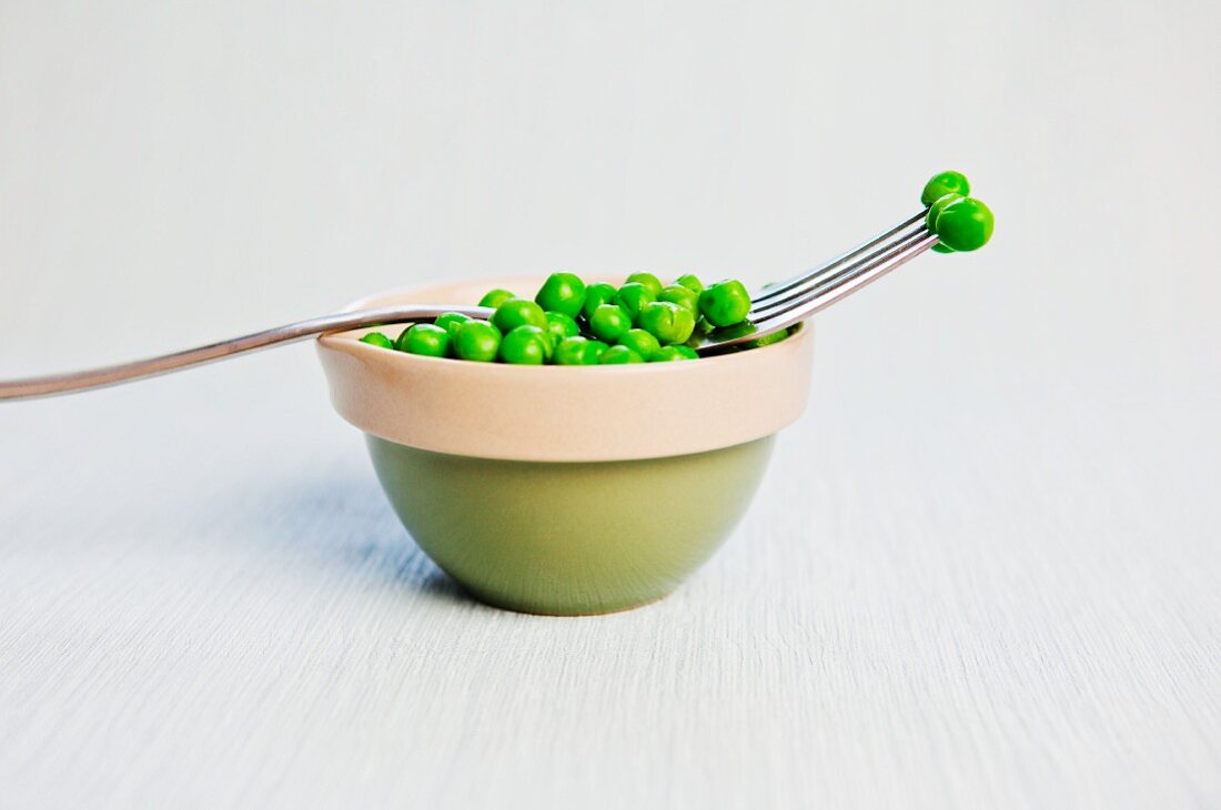 A bowl of peas with a fork