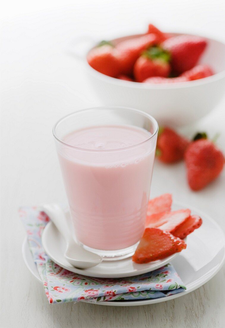 A glass of strawberry milkshake and fresh strawberries