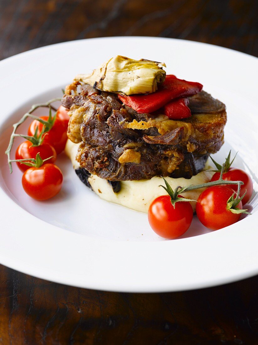 Lamb on a bed of mashed potatoes with artichokes and tomatoes