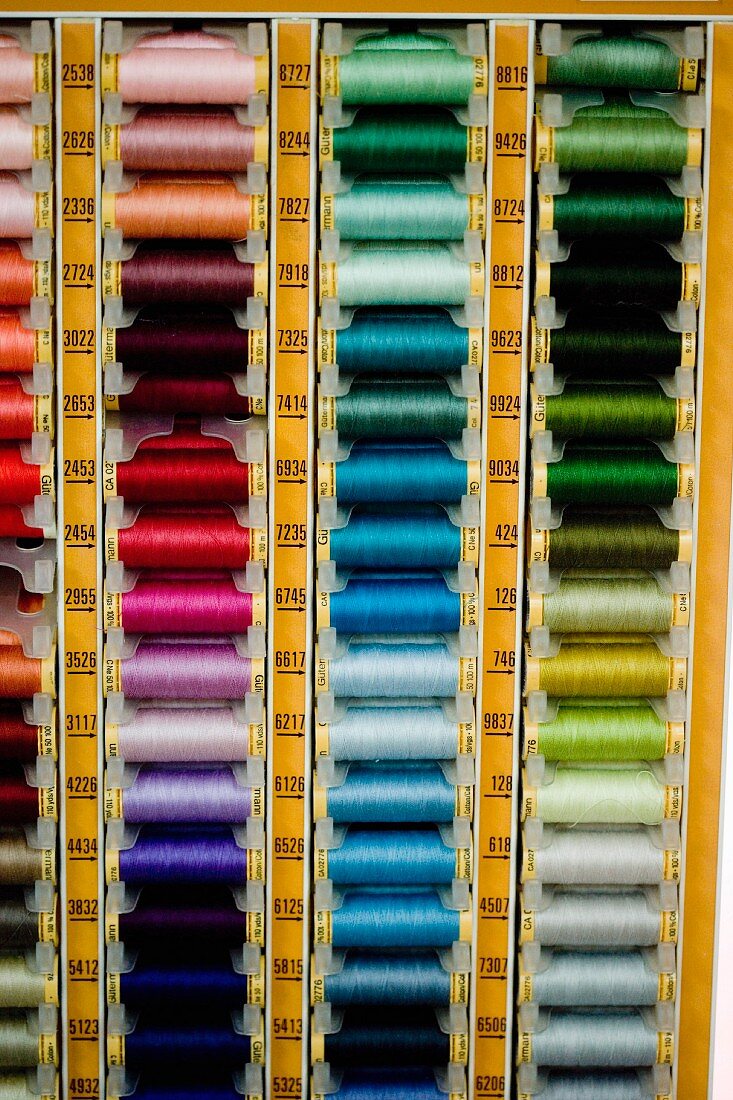 Spools of thread in various colours arranged in rack