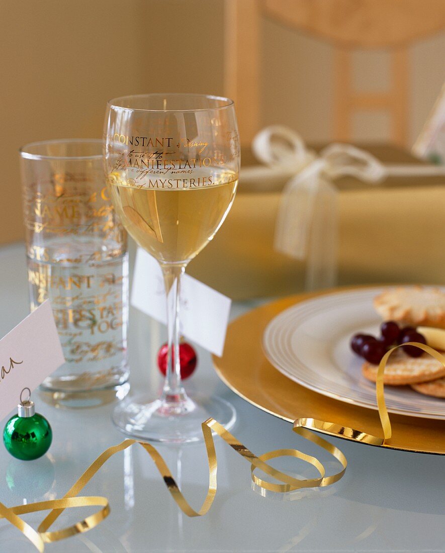 A glass of white wine and snacks on a table laid for Christmas dinner