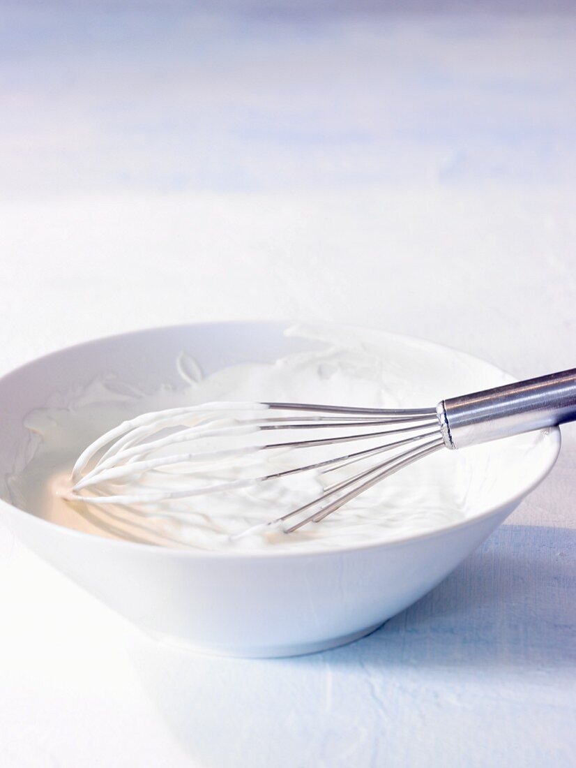 A bowl of yogurt with a whisk