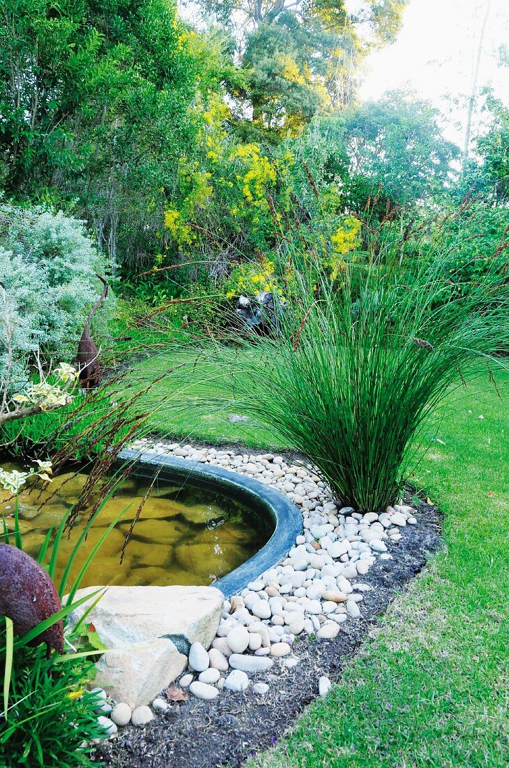 Round pond surrounded by pebbles and plants