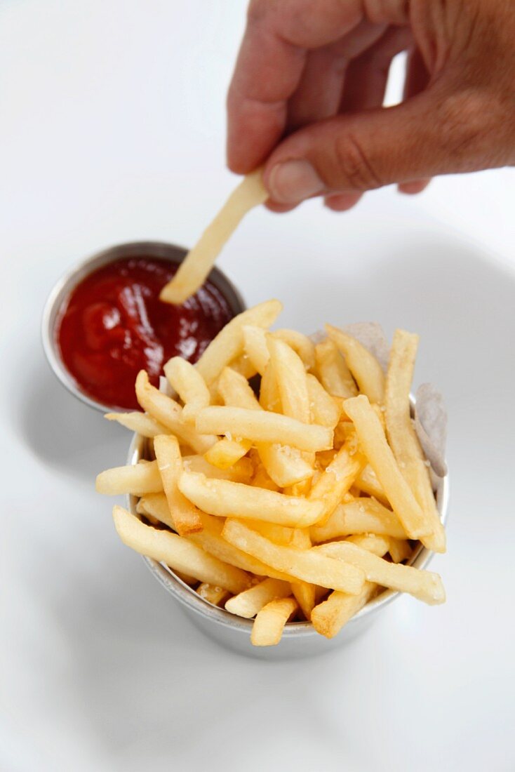 Chips being dipped into ketchup