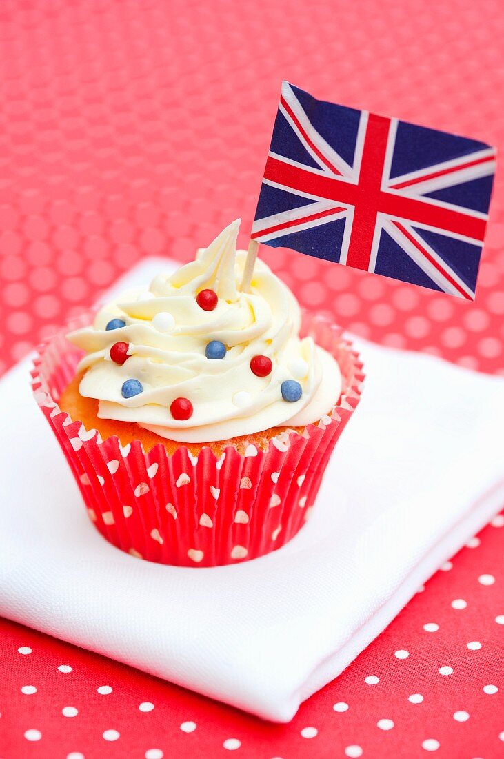 A cupcake decorated with a small flag and sugar beads