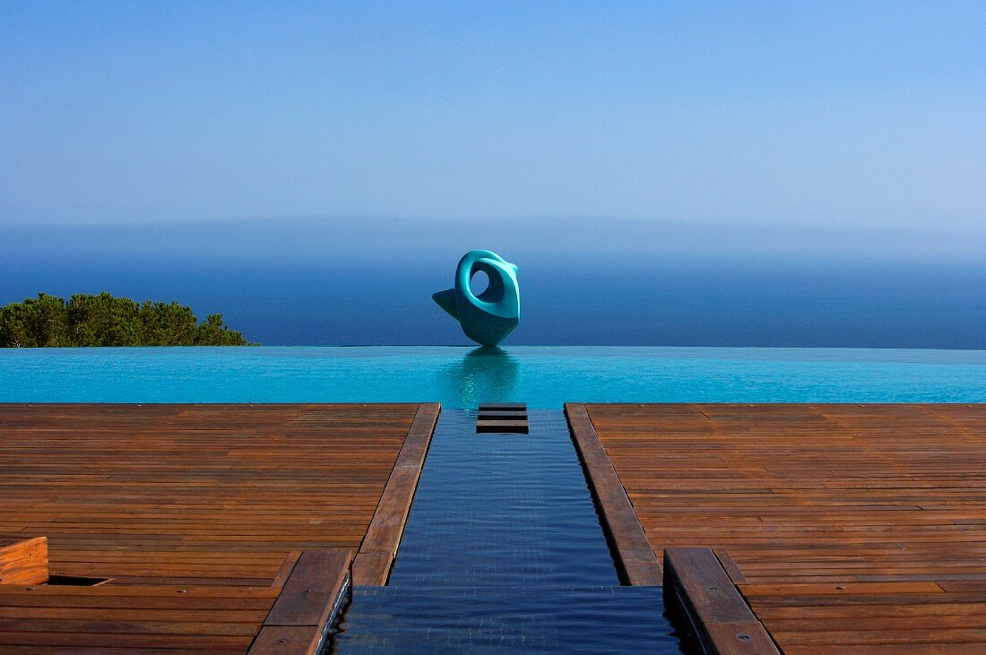 Grosszügige Holzterrasse mit Wasserkanal zu dem Infinity-Pool und mit Blick auf das Meer