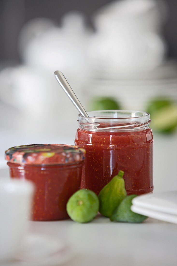 Two jars of strawberry jam and fresh figs