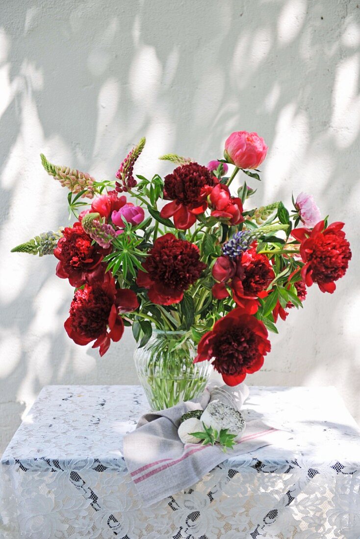Flamboyant summer bouquet on table with pattern of light and shade on exterior wall