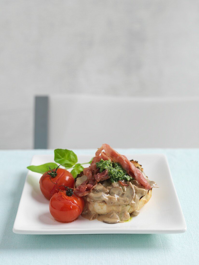 A bagel with mushroom sauce, bacon and tomatoes