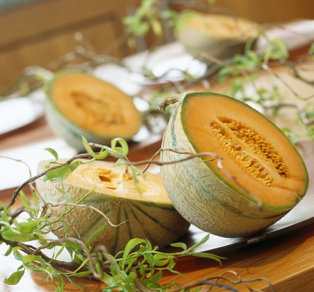 A halved melon decorated with twigs on a table