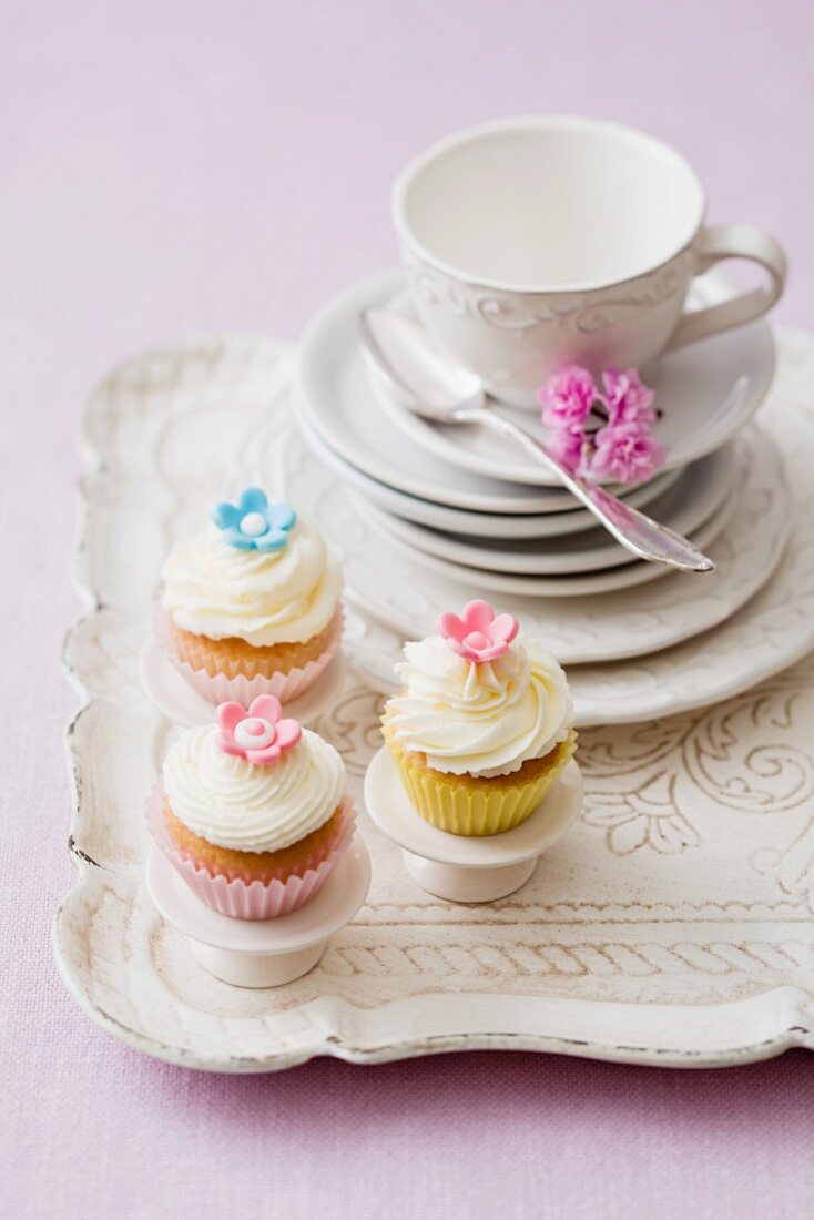 Drei Cupcakes mit Tellerstapel und Teetasse