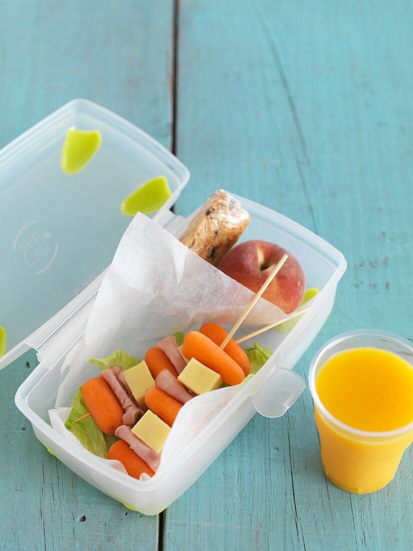 Lunchbox mit Möhrenspiesschen und Orangensaft für die Schule
