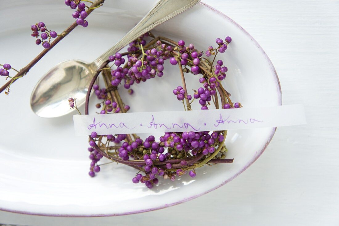 Wreath of callicarpa and name tag next to silver spoon in dish