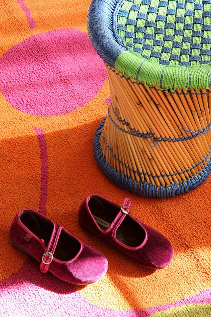 Bamboo stool and girl's shoes on colourful rug