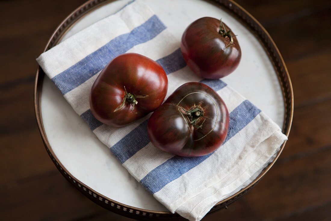 Drei Heirloom Tomaten mit Küchentuch auf einem Tablett