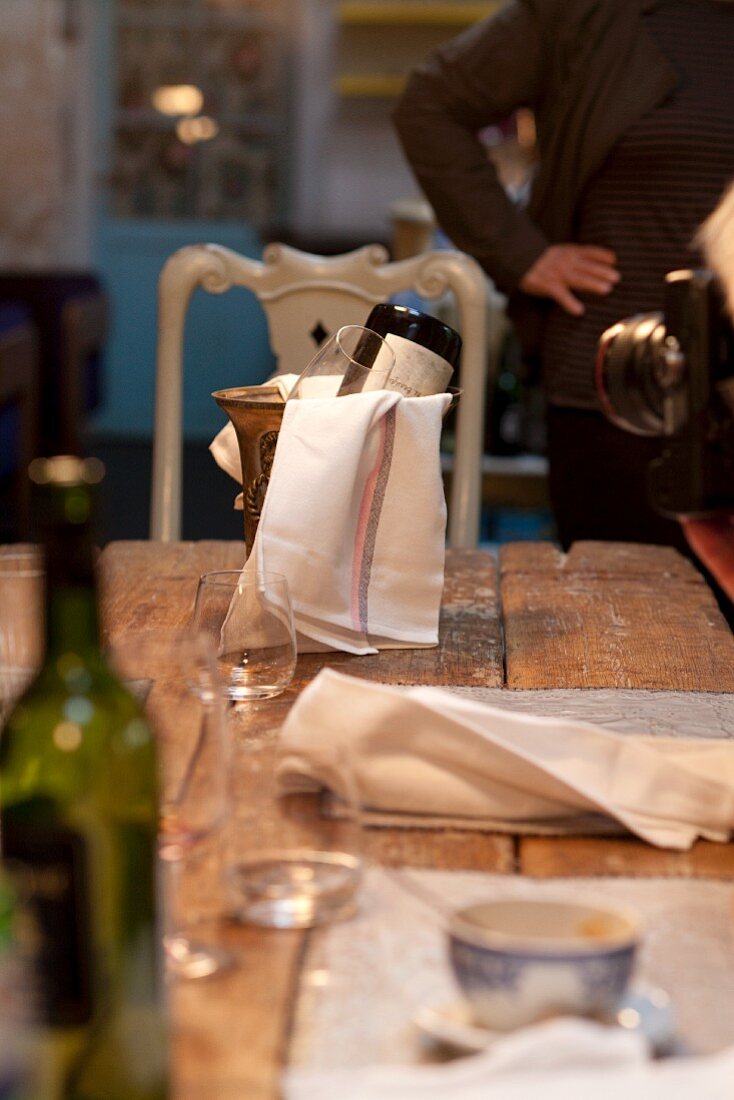 Weinflasche, Weingläser und Sektkühler auf einem Holztisch