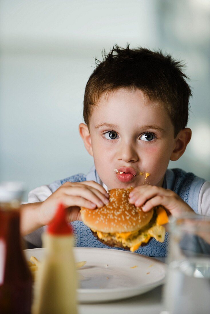 A little boy eating a cheeseburger