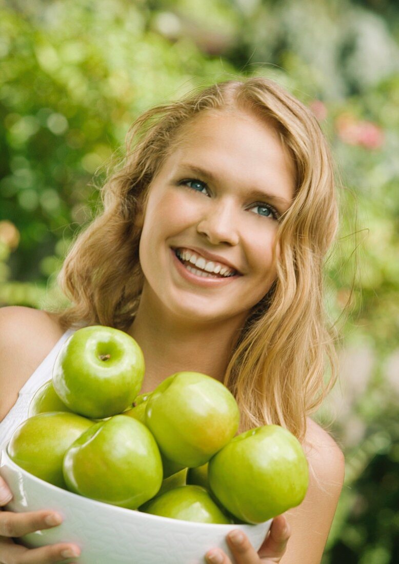 Junge Frau hält eine Schale Äpfel