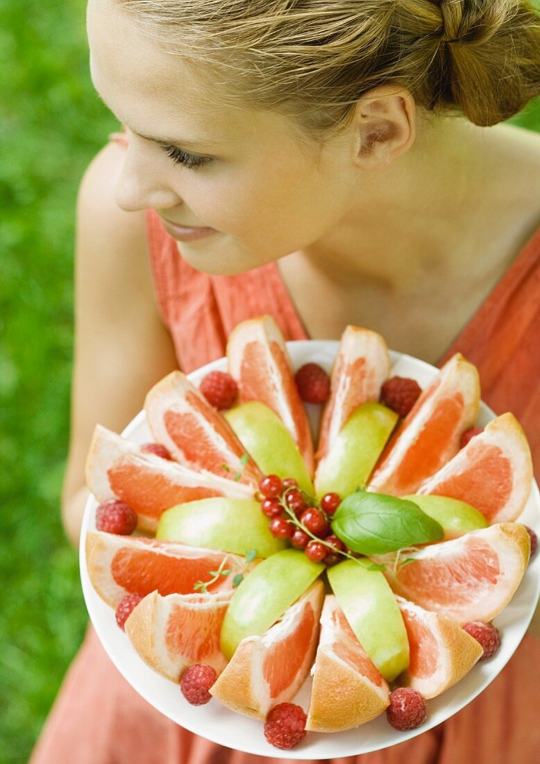 Junge Frau hält einen Obstteller