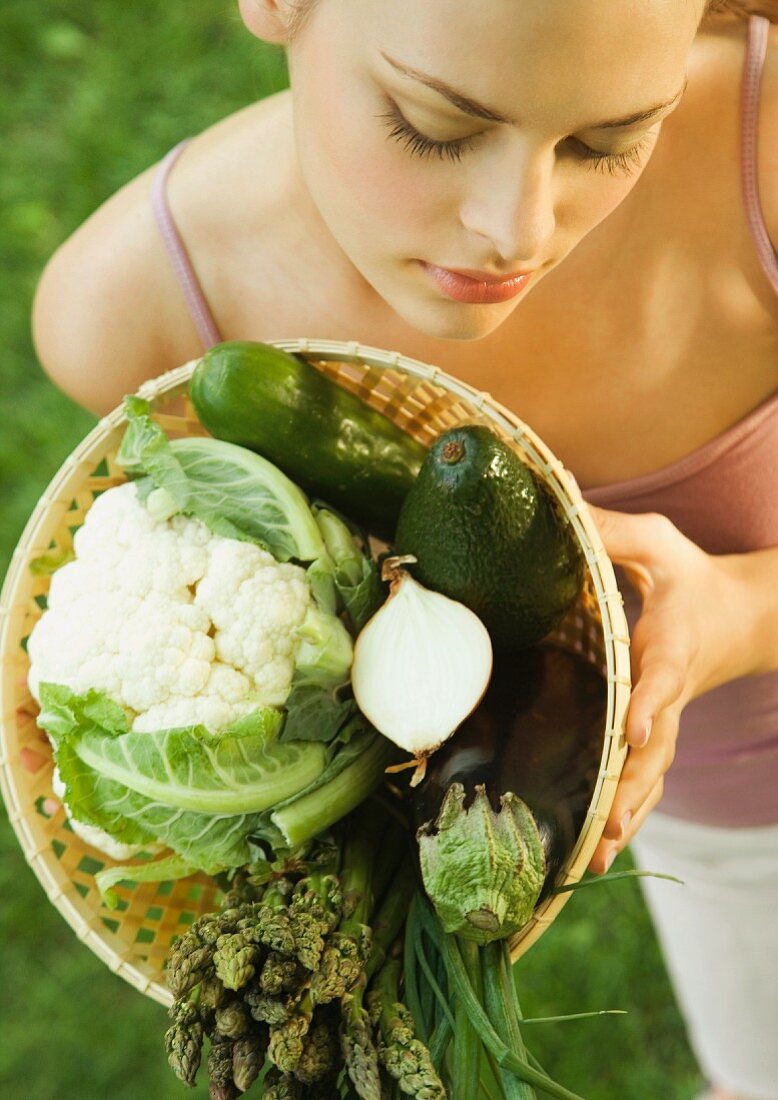 Junge Frau hält einen Gemüsekorb