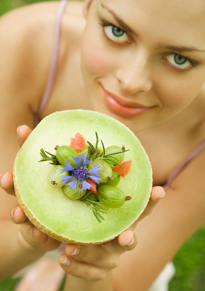 Young woman holding up melon bowl of fruit