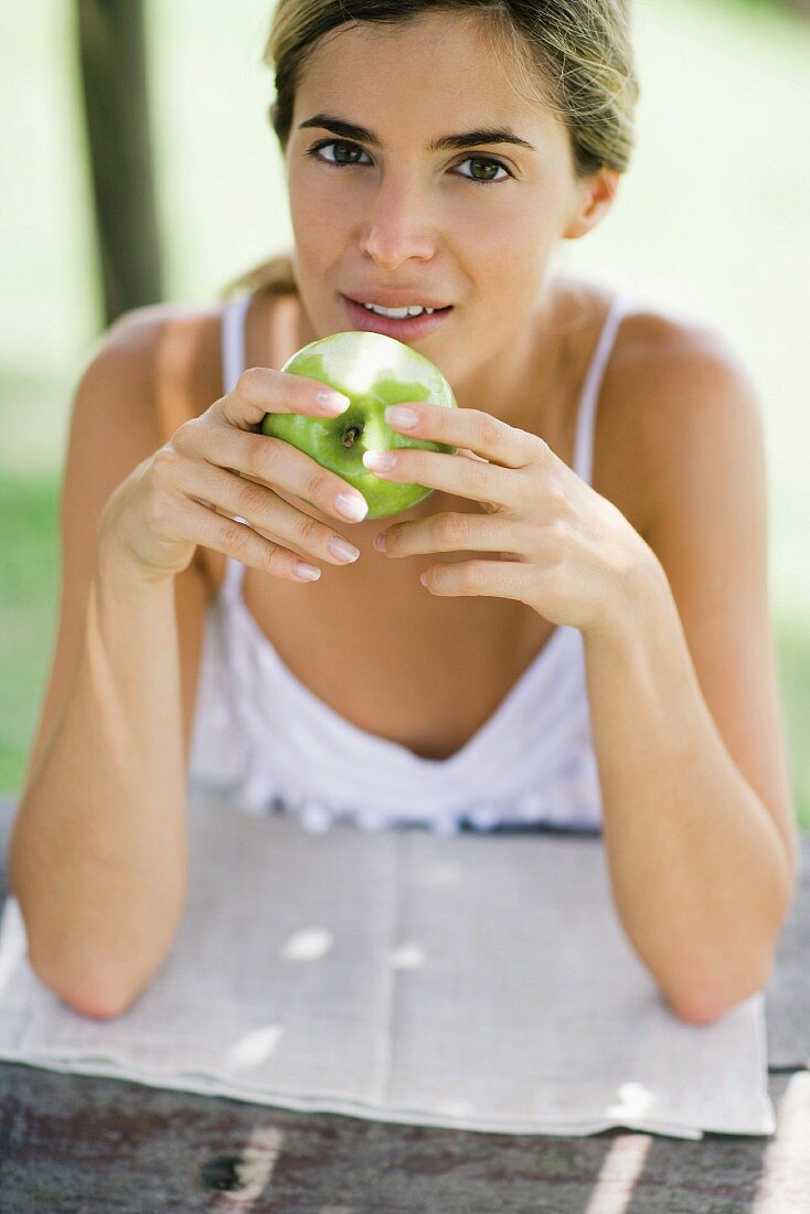 A woman holding a green apple