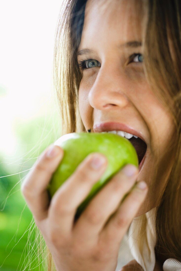 Junge Frau beisst in einen grünen Apfel
