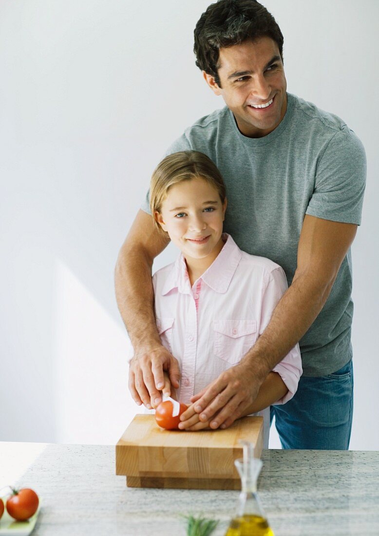 Vater hilft Tochter beim Tomatenschneiden