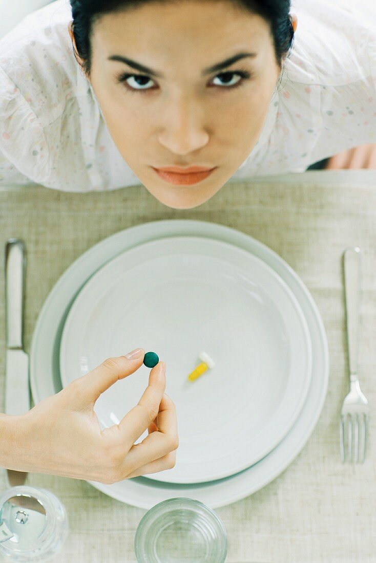 Frau isst Vitamintabletten vom leeren Teller