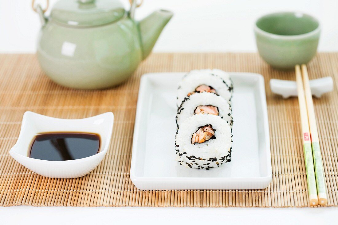 Maki-Sushi, Sojasauce, Essstäbchen und Tee