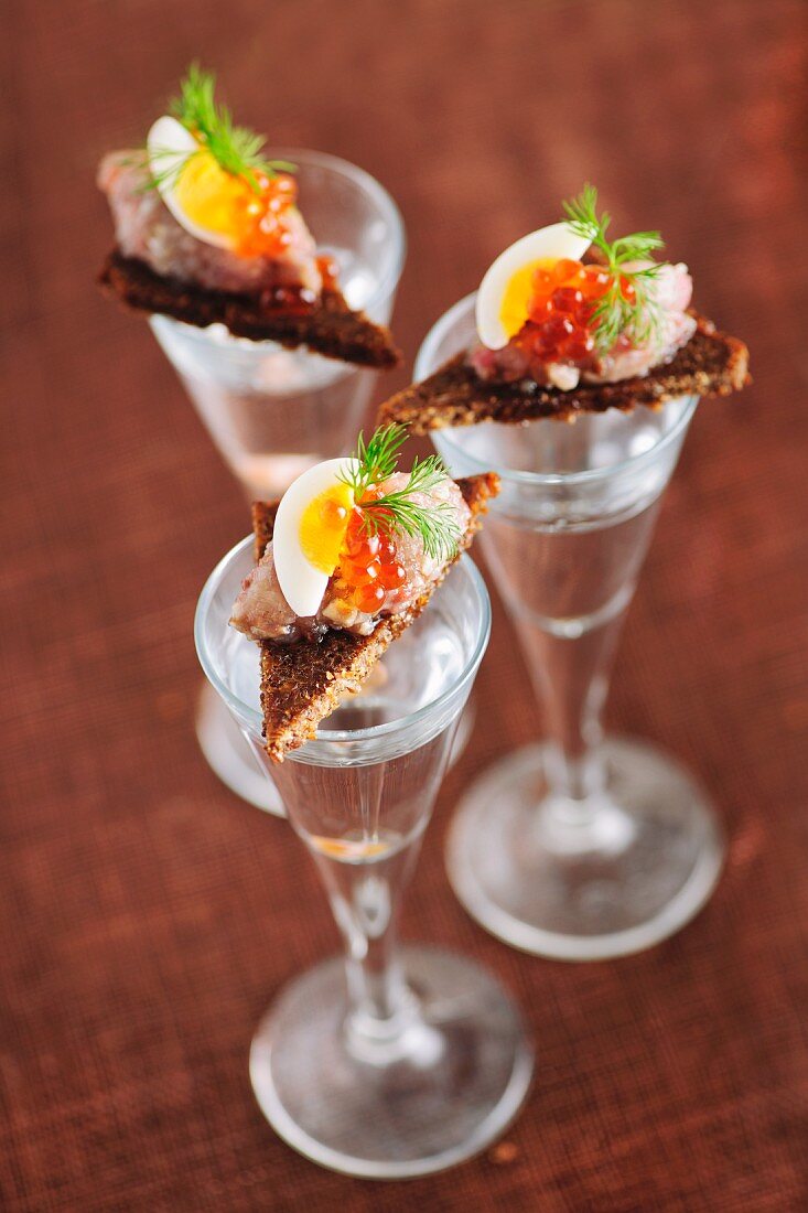 Canapés with herring tartar on vodka glasses